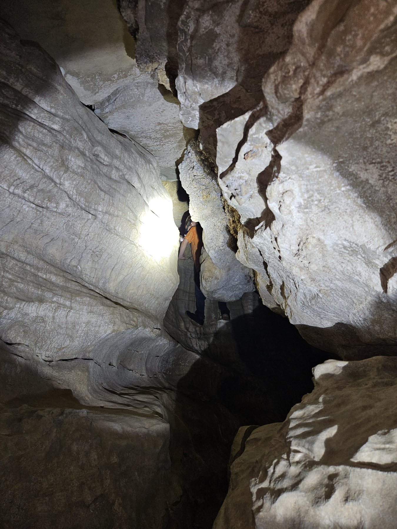 George squeezing between pale rock walls inside Laurel Cave
