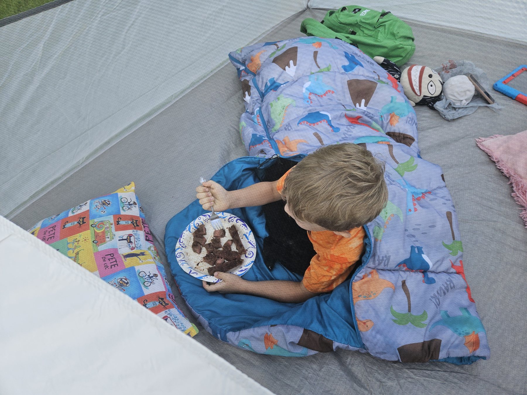 George eating steak while tucked into a sleeping bag
