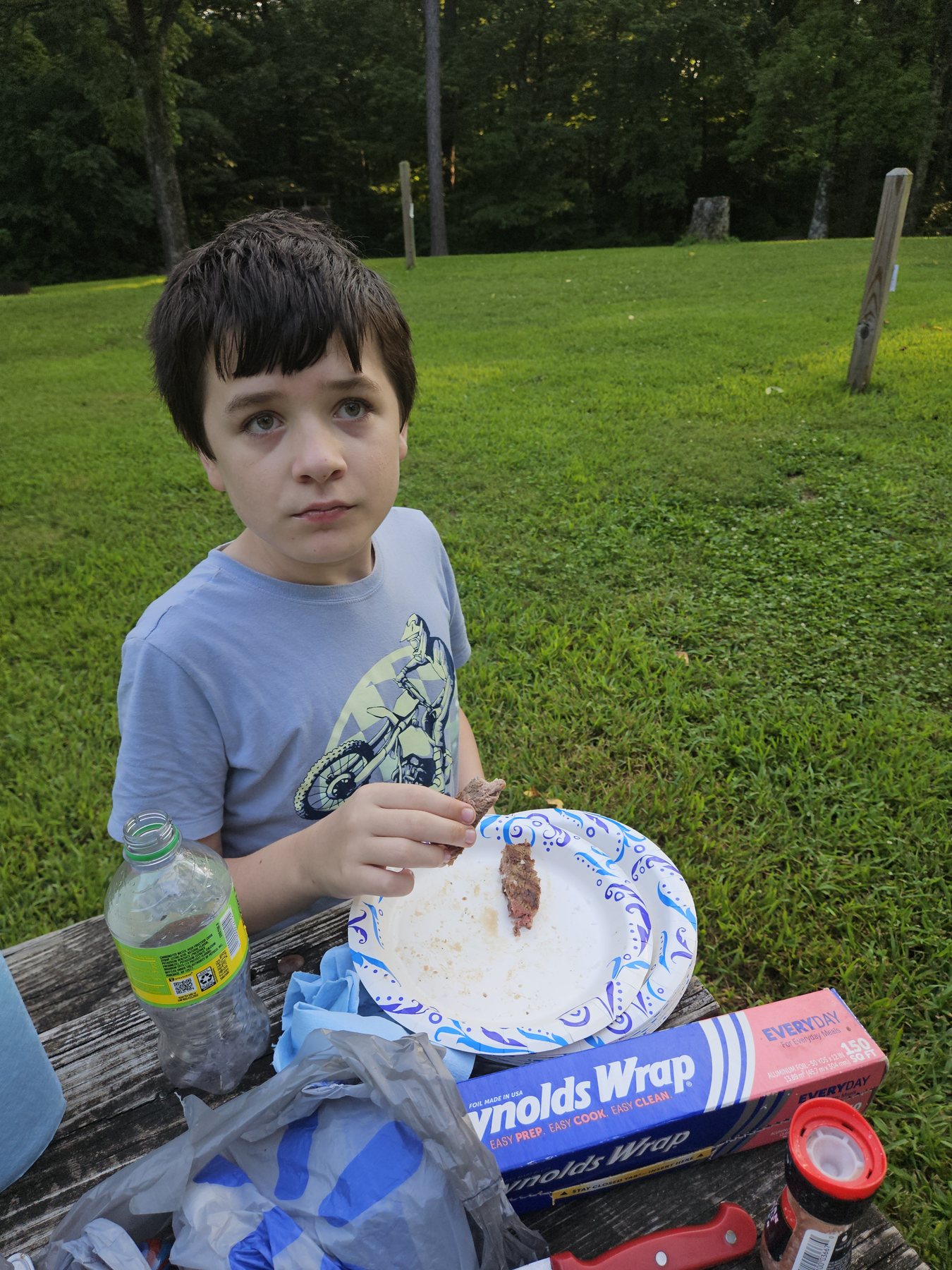 Mason eating steak at the campsite picnic table