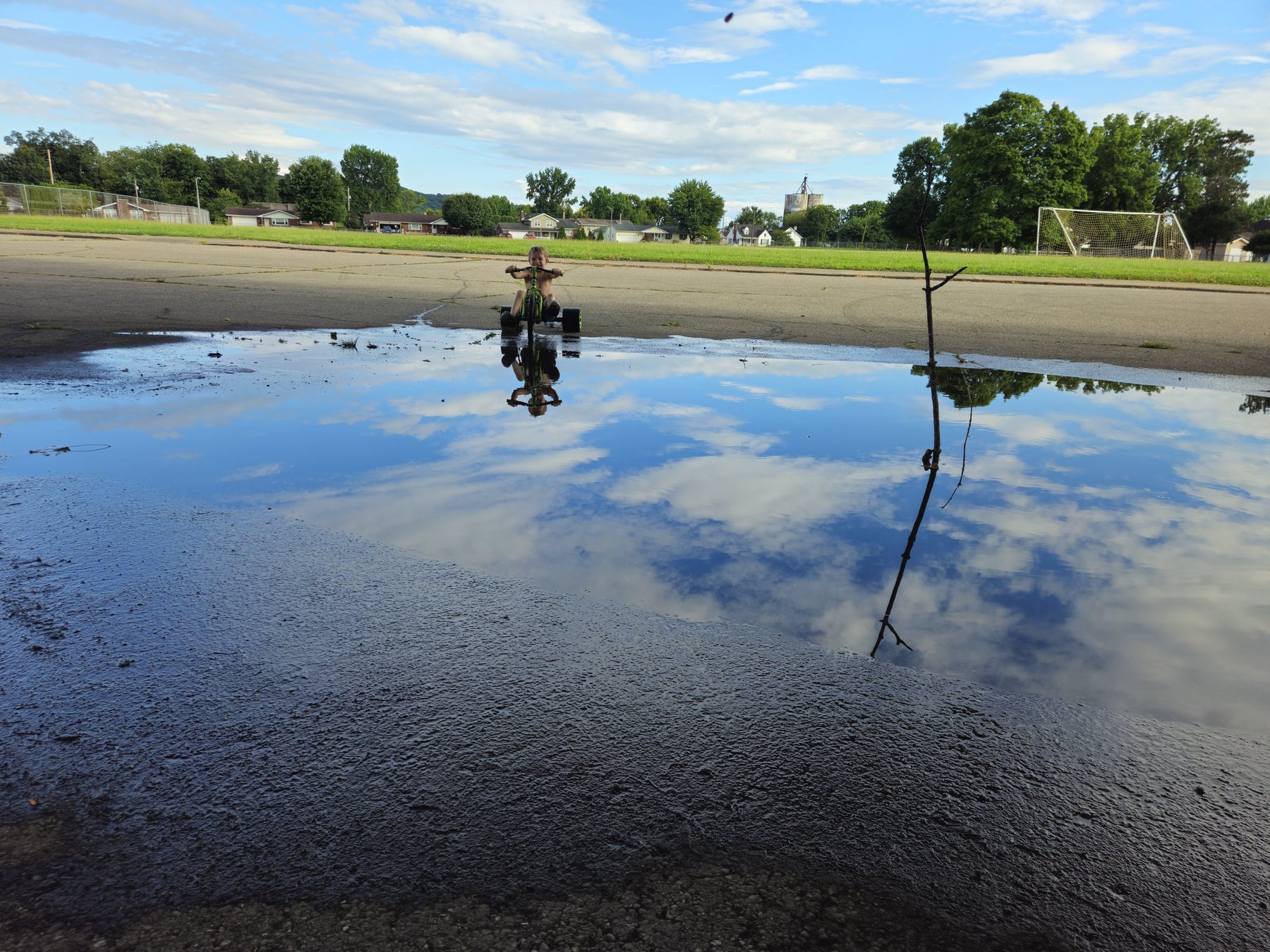 George riding his Big Wheel toward a puddle reflecting the blue sky