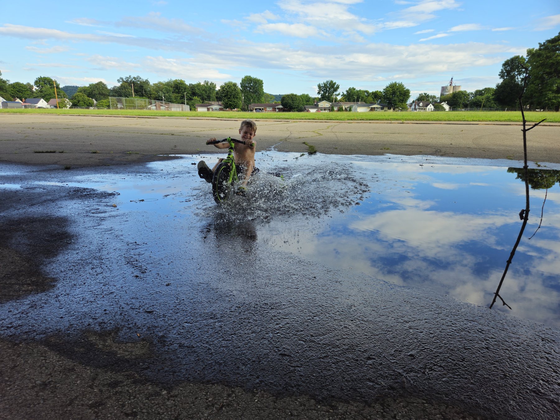 George splashing through a large puddle on his Big Wheel