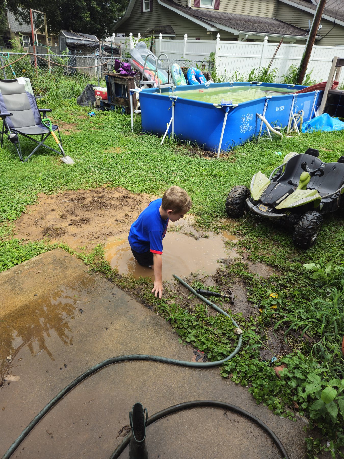 George crouching and playing in the muddy rain-filled hole